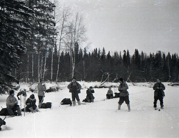 Zolotaryov, Zina, Rustem, Doroshchenko, Kolevatov, Lyuda, Kolya, Dyatlov. Three hikers are looking at Rustem, who says something and they listen attentively.