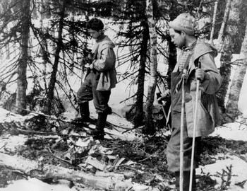 Free search. Suvorov and Askinadzi on the site of the storage. A log, spruce branches and chopped twigs are visible.