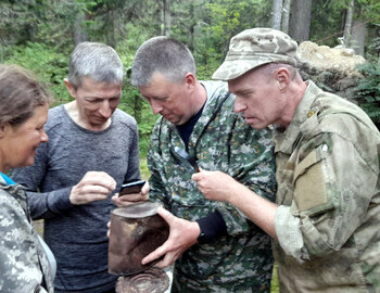 Valentina Palkina, Shura Aleeksenkov, Sergey Ipatov and Aleksey Komanyov (aka Korolyov) examine an old tin can from stew found at the possible second location of the 1959 searcher's camp, which Shura Alekseenkov is investigating
