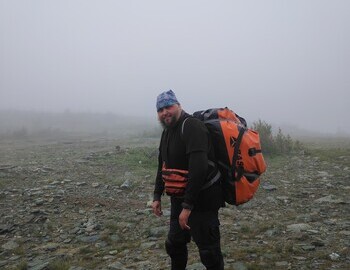 Artyom carrying his boat, Dyatlov Pass, photo by Ira Tolmatskaya